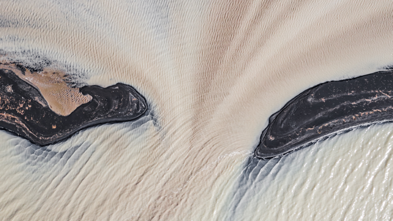 Image of glacial meltwater on black sand beaches and a braided river photographed from directly above in Iceland