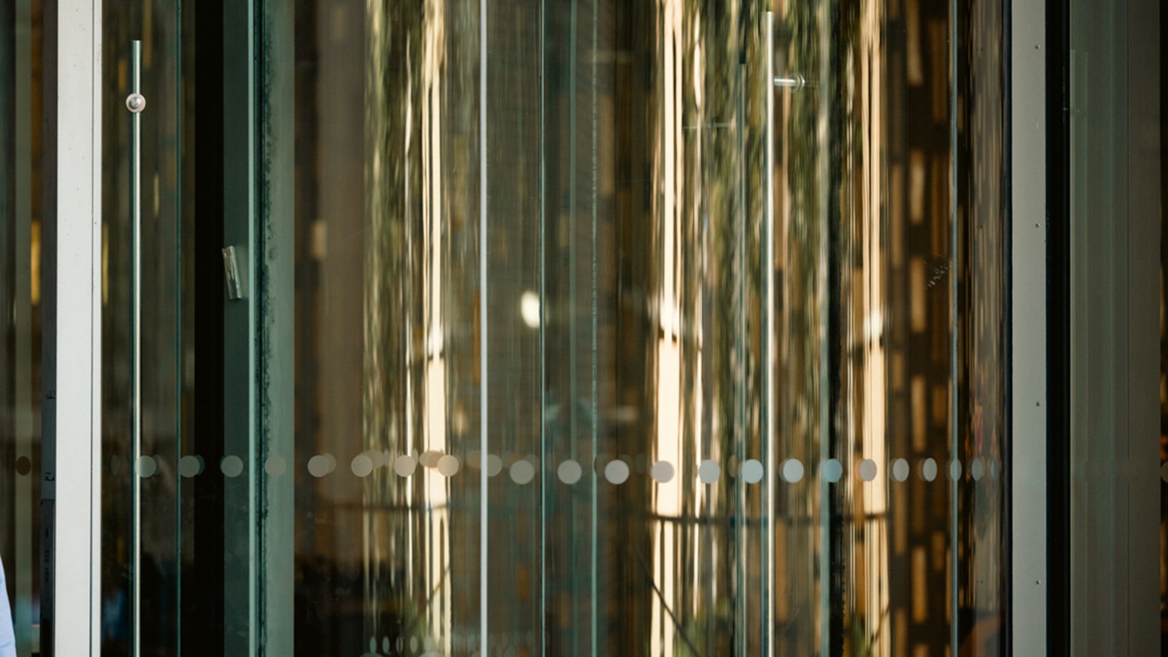 Reflective glass panels create abstract patterns of light and texture within a contemporary office building interior.