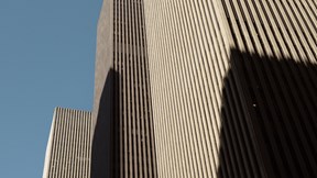 Upward view of Rothschild & Co’s New York office at Avenue of the Americas, showing the modern skyscraper façade rising between neighbouring high-rise buildings against the sky.