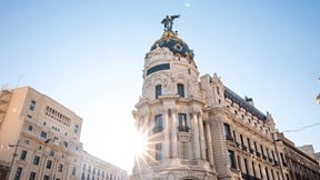 View upwards into the sun of an art nouveau corner building with blue sky above