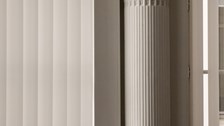 Close-up of interior architectural details featuring vertical white columns, panels and mouldings. The image emphasises clean lines, symmetry and the texture of the historic building interior.