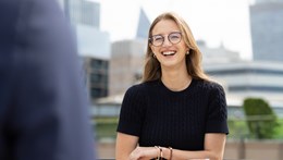 Young professional in conversation with someone out of frame, with city skyline beind