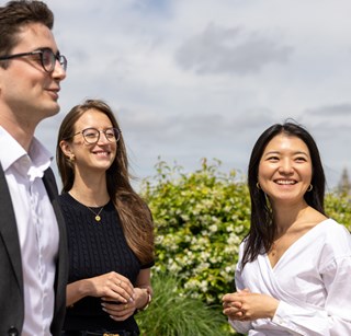 Three young professionals interacting casually on a rooftop with the city skyline behind