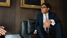 Young professional seated in a wood-panneled office space with a gold-framed oil portrait behind