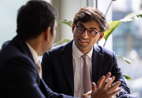 Two colleagues in conversation in a modern office environment.