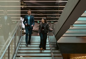 Two professional people descending a staircase in a modern office