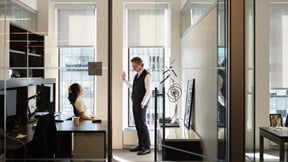Two professionals in conversation in a a glass office in a light bright office environment