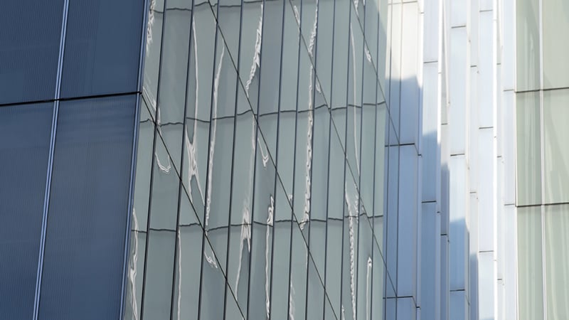 Close-up view of the exterior of New Court, a modern glass building, showing reflections and geometric patterns on the windows.