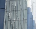 Close-up view of the exterior of New Court, a modern glass building, showing reflections and geometric patterns on the windows.