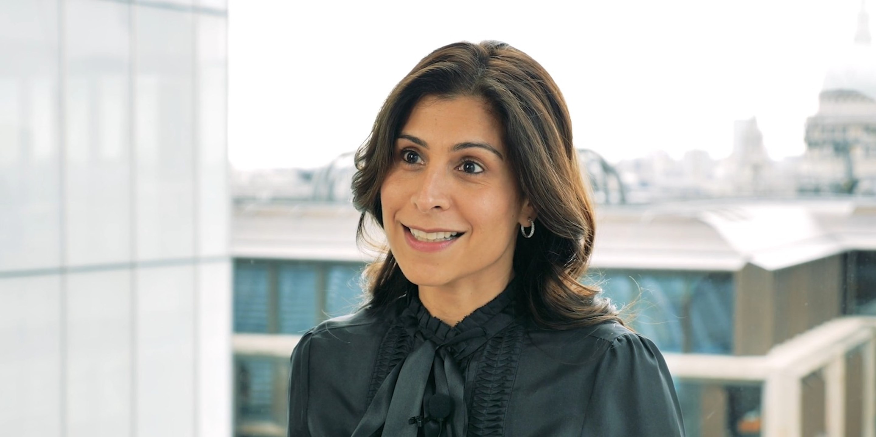 Colleague featured in a career relaunch video, standing in a modern office workspace.