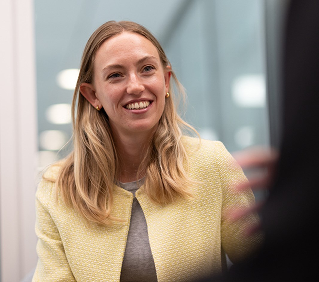 A Rothschild & Co colleague seated at a meeting table in a modern office, speaking to another colleague.