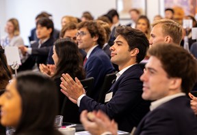Audience members seated at a training event applauding a presentation.