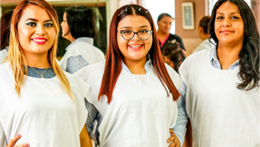 Group of women training in cosmetology wearing aprons and smiling