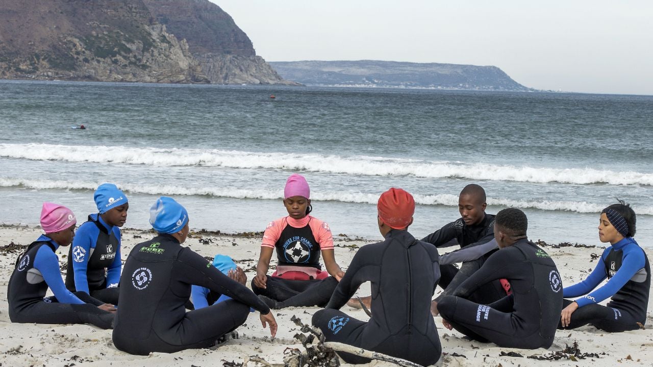 Children sat on beach in wesuits