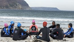 Children sat on beach in wesuits