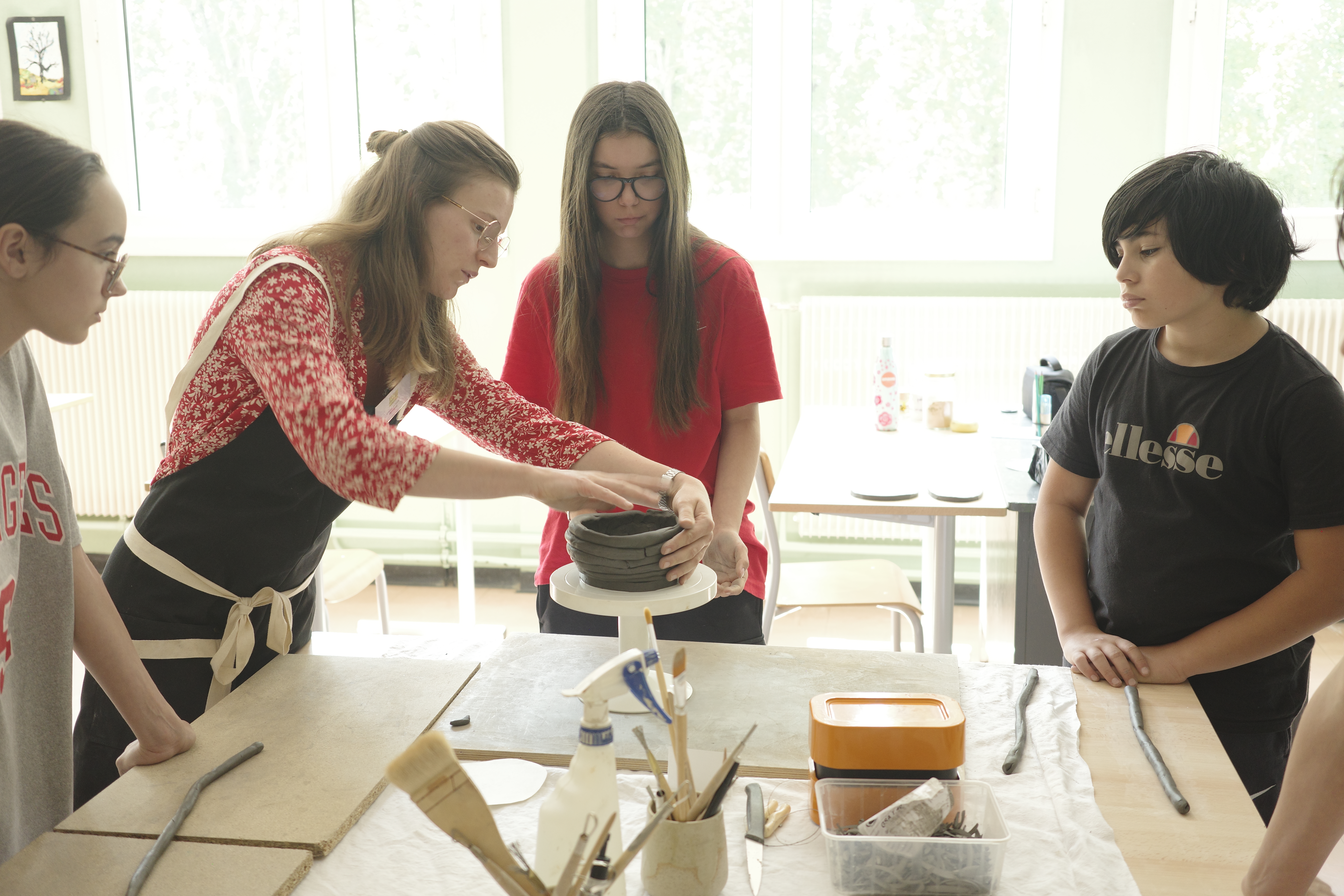 children watching an artisan make pottery