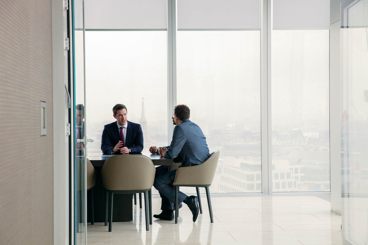 Three people sat down around a table  having a meeting