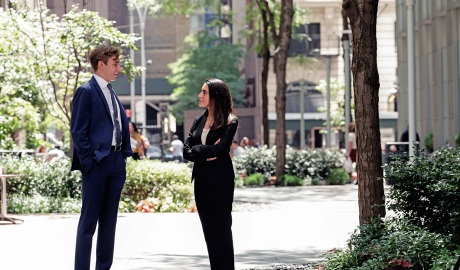 Two people having a conversation outside in a city green space