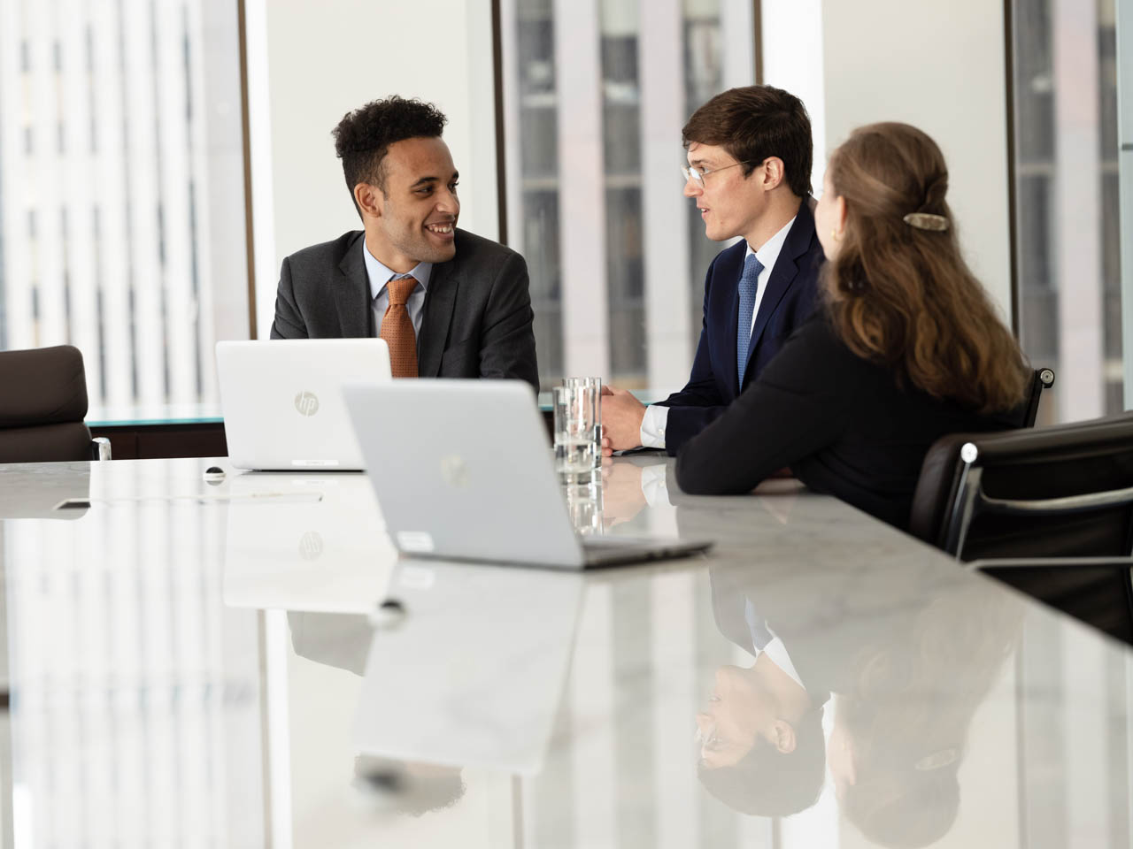 Three people sat at a meeting table