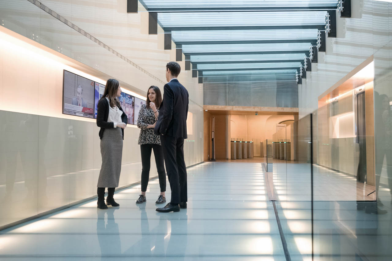 Three people having a discussion in a hallway