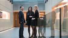 Three people having a discussion in a hallway