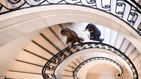 Two people climbing up a spiral staircase.