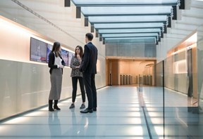 Three people conversing in a sky lit hallway 