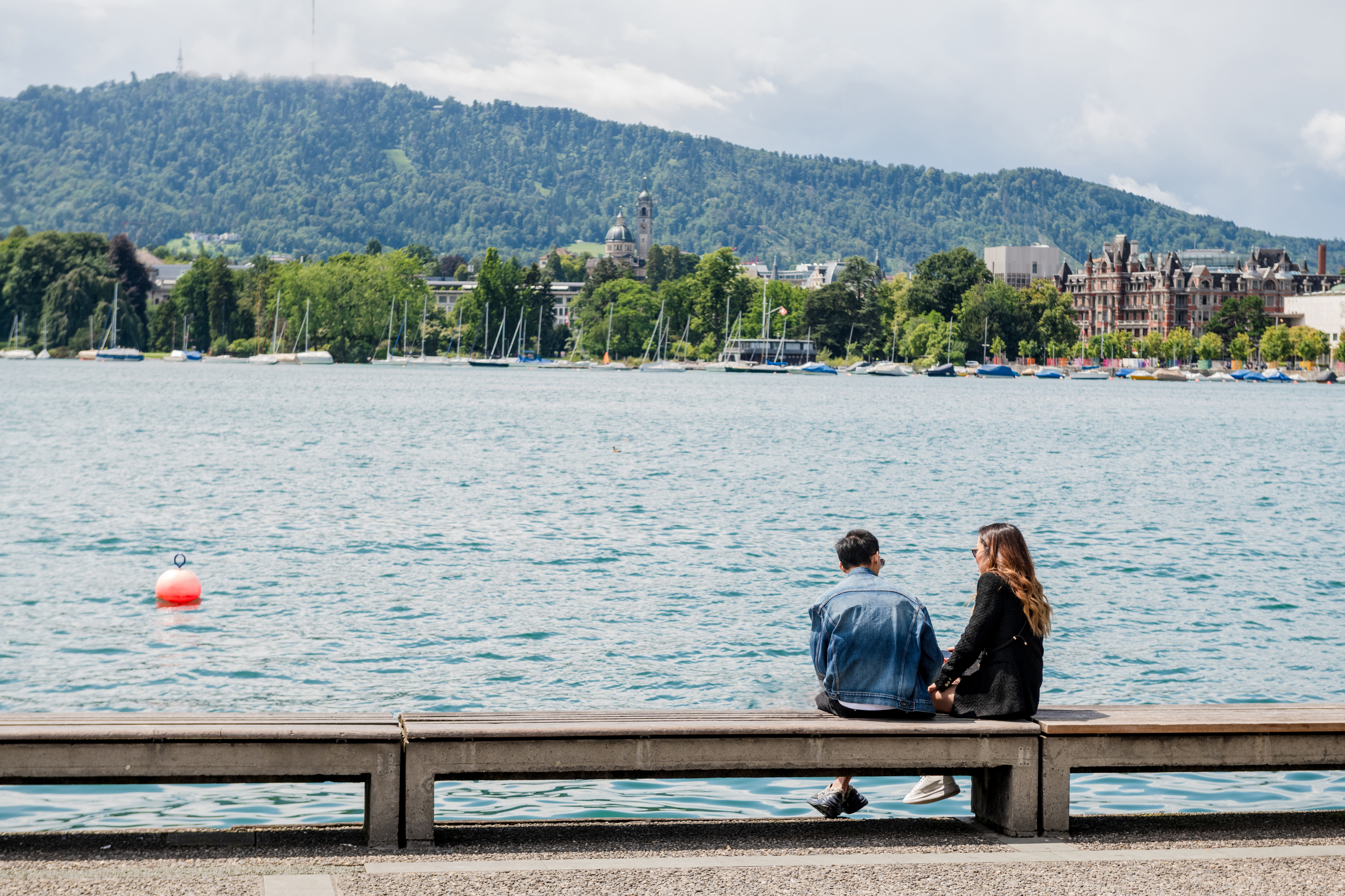 Two persons sititng in front of the Zurich lake 