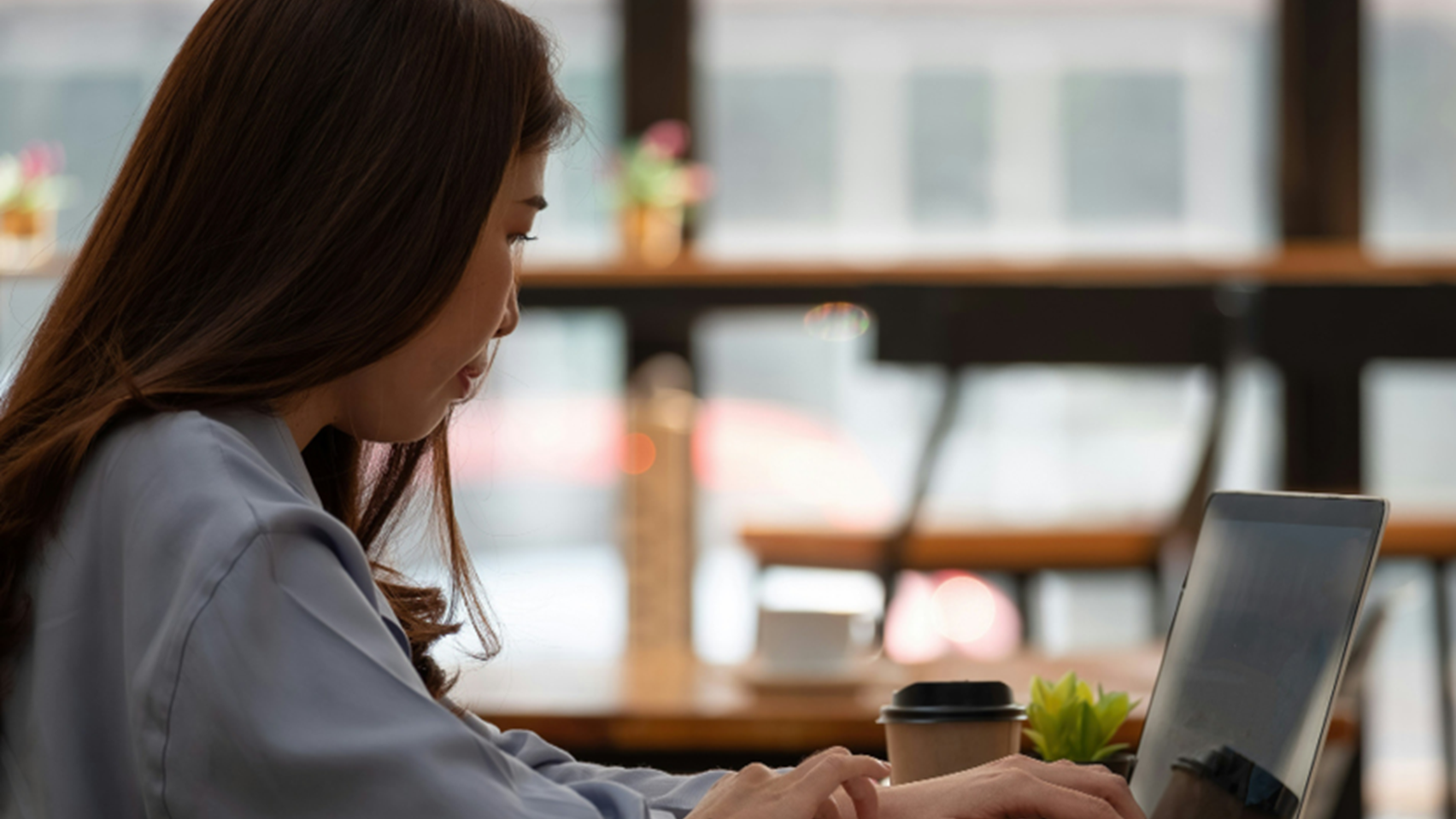 A woman working on a laptop in a cafe