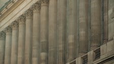 Classical stone building facade featuring a row of large architectural columns