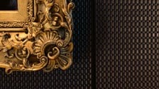 Ornate gilded picture frame detail against a dark textured wall
