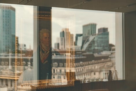 Image of a Rothschild family painting with a reflection behind it of the City of London skyline