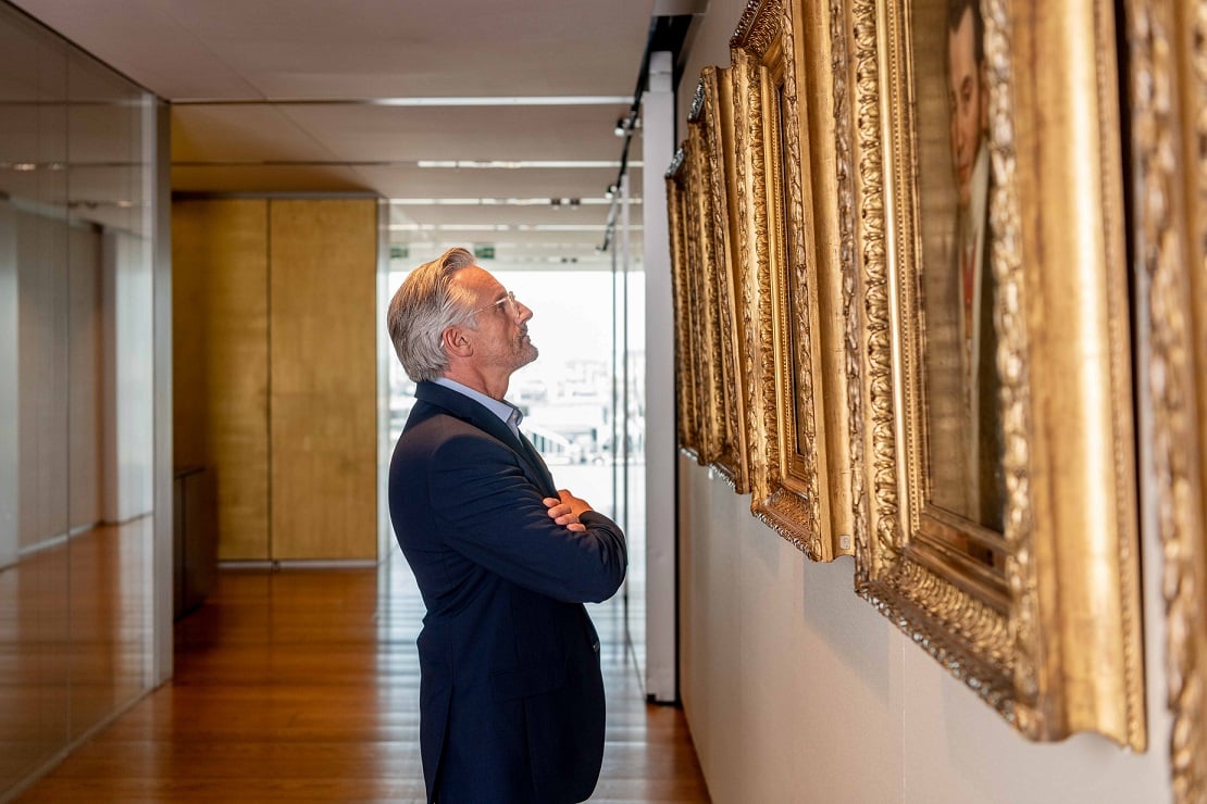 Man looking at gold framed family portraits