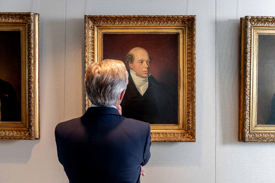 Man admiring family portrait paintings in gold frames