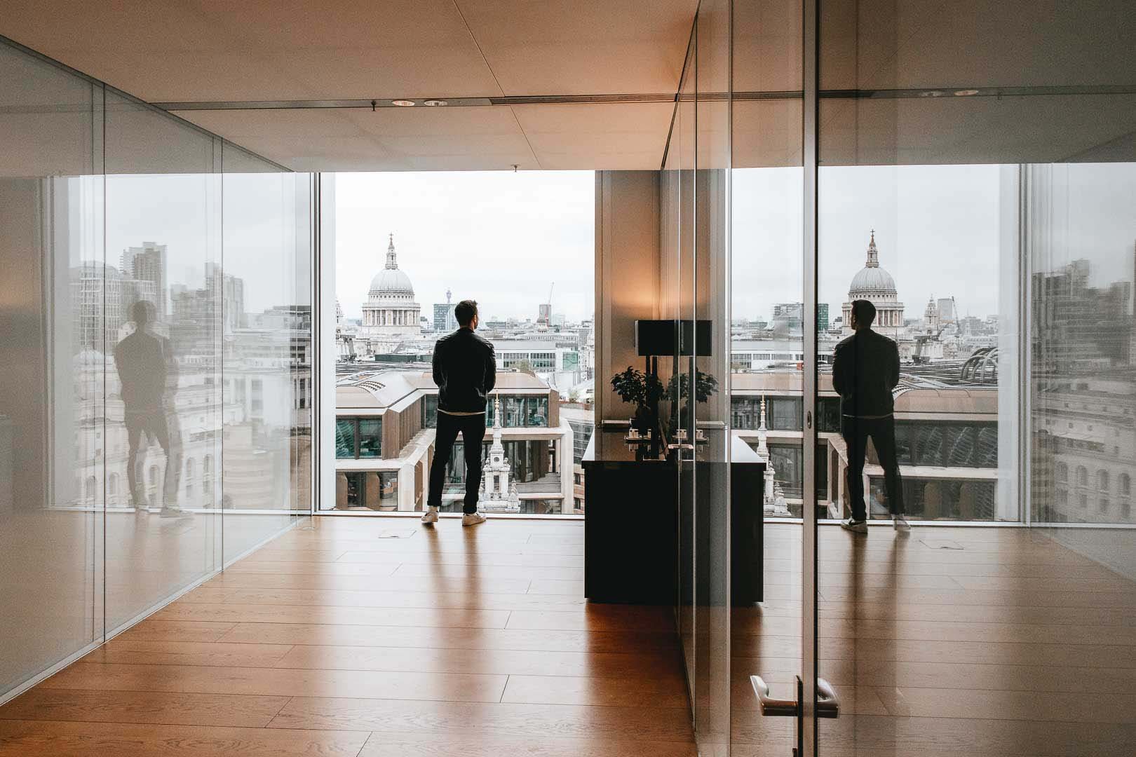 Man overlooking city skyline with his reflection in glass