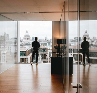 Man overlooking city skyline with his reflection in glass