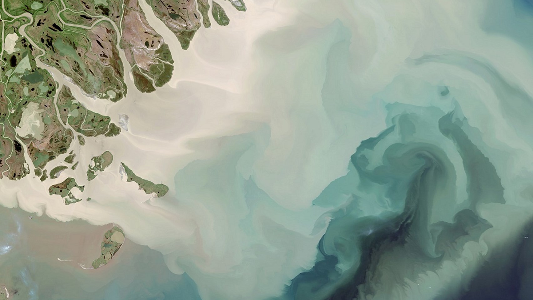 Image of a light blue river running through green land
