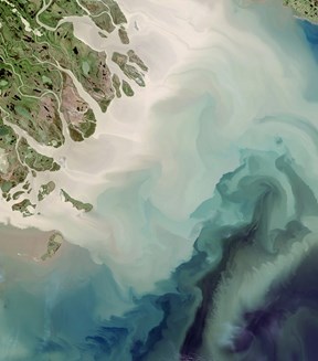 Image of a light blue river running through green land