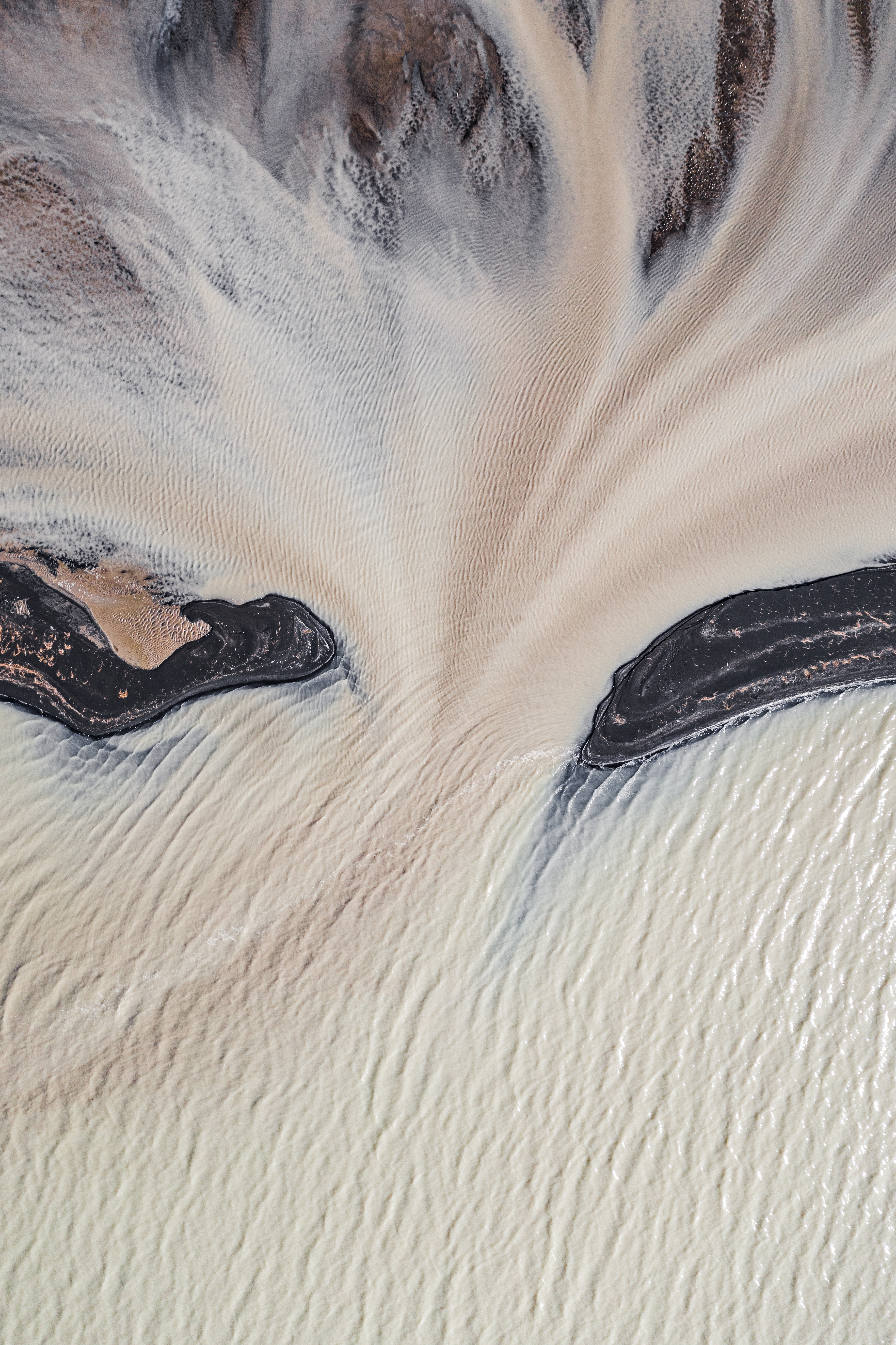 Image of glacial meltwater on black sand beaches and a braided river photographed from directly above in Iceland