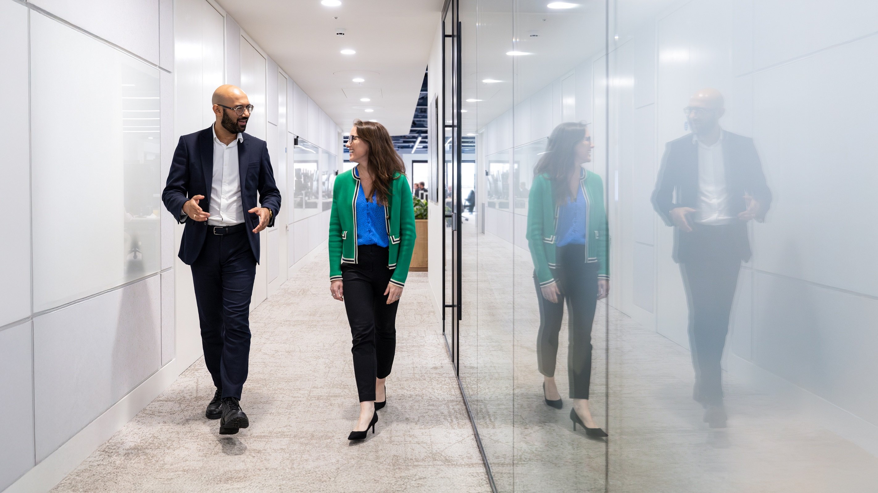 Male and female colleague walking in the offices of Rothschild & Co Redburn