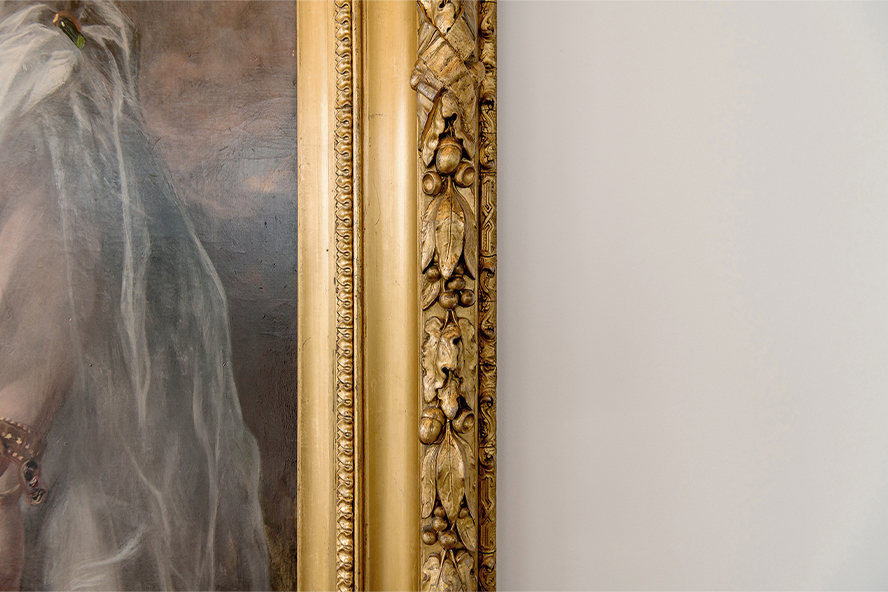 Close-up image of a painting with a gold frame on a white wall