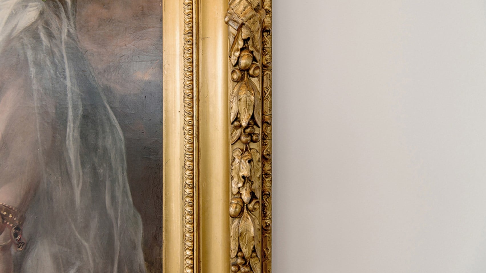 Close-up image of a painting with a gold frame on  a white wall