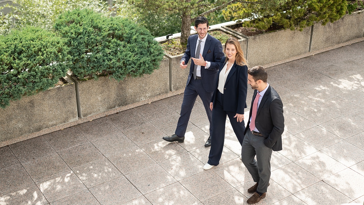 Three Rothschild & Co colleagues walking outside with green area behind them