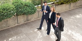 Three Rothschild & Co colleagues walking outside with green area behind them